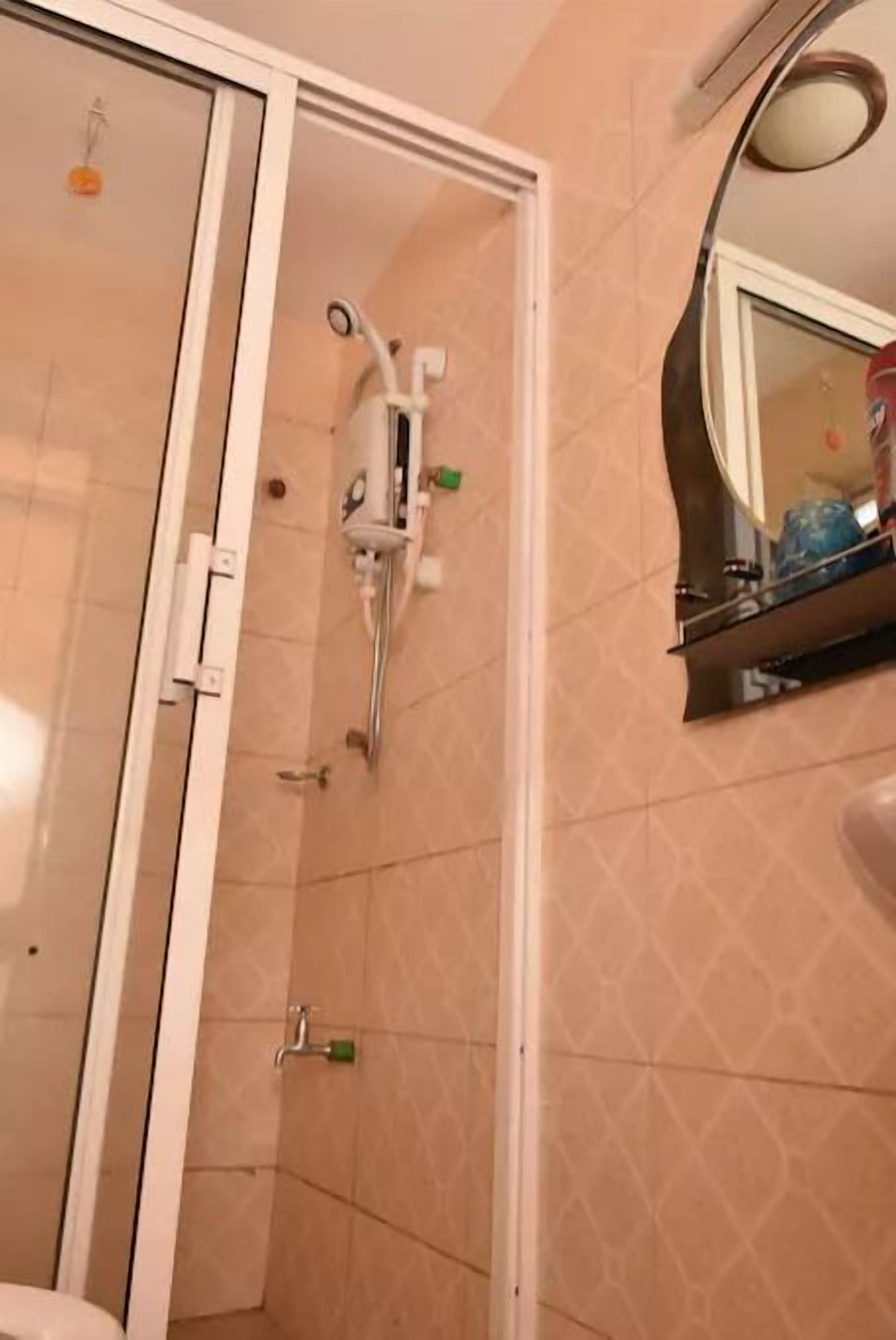 Une salle de bain avec une douche à parois de verre, un lavabo avec un miroir au-dessus et des toilettes visibles à travers la porte de la douche.