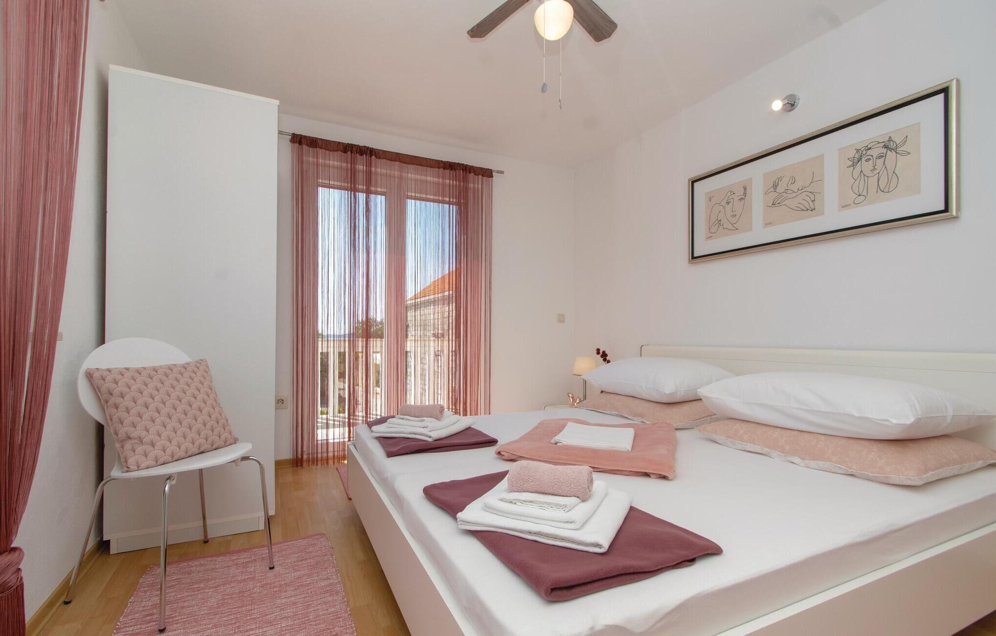 A bedroom with a bed, a chair, a desk, and a window with curtains.
