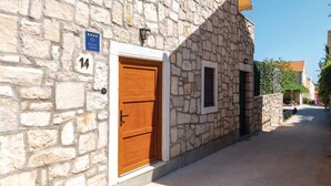Un bâtiment en pierre avec une porte en bois et une petite fenêtre. Il y a une enseigne avec des étoiles et le texte « KUČAZA ODOMOR » ainsi que le numéro « 14 ».