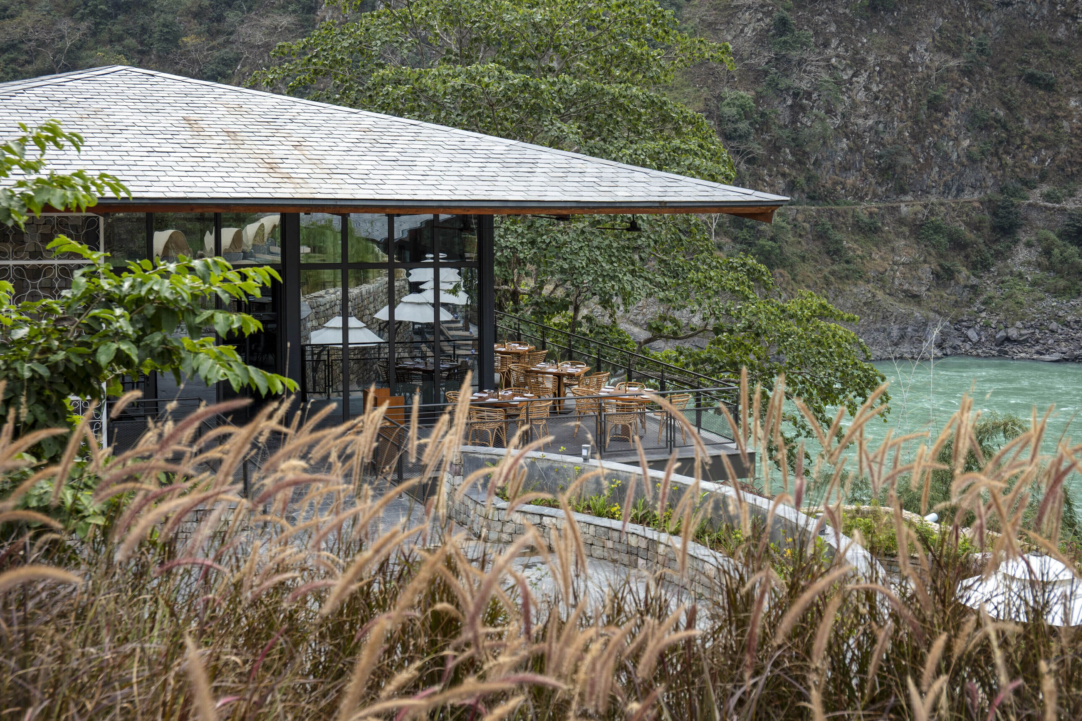 A building with a glass facade, outdoor seating, and a view of a mountainous landscape.