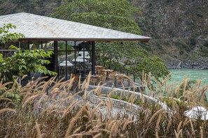 A building with a glass facade, outdoor seating, and a view of a mountainous landscape.