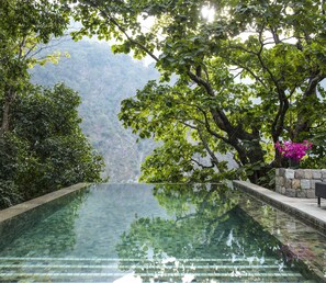 A clear infinity pool with a view of a mountainous landscape.