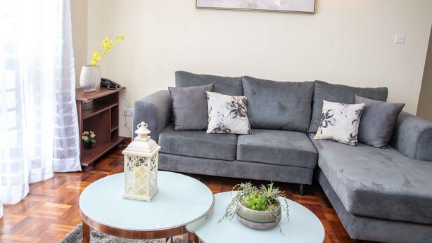 A living room with a grey sofa, two round coffee tables, a white lantern, and a framed artwork on the wall.