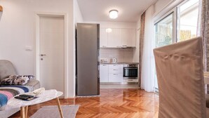 Une cuisine moderne avec des meubles blancs, un réfrigérateur en acier inoxydable et un four encastré.