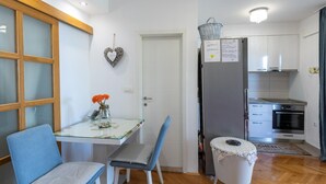Une cuisine compacte équipée d’un réfrigérateur, d’un four et d’une petite table à manger avec des chaises.