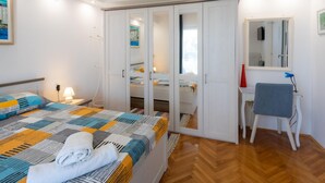Une chambre à coucher comprenant un lit, un bureau, une chaise, une armoire et un miroir.