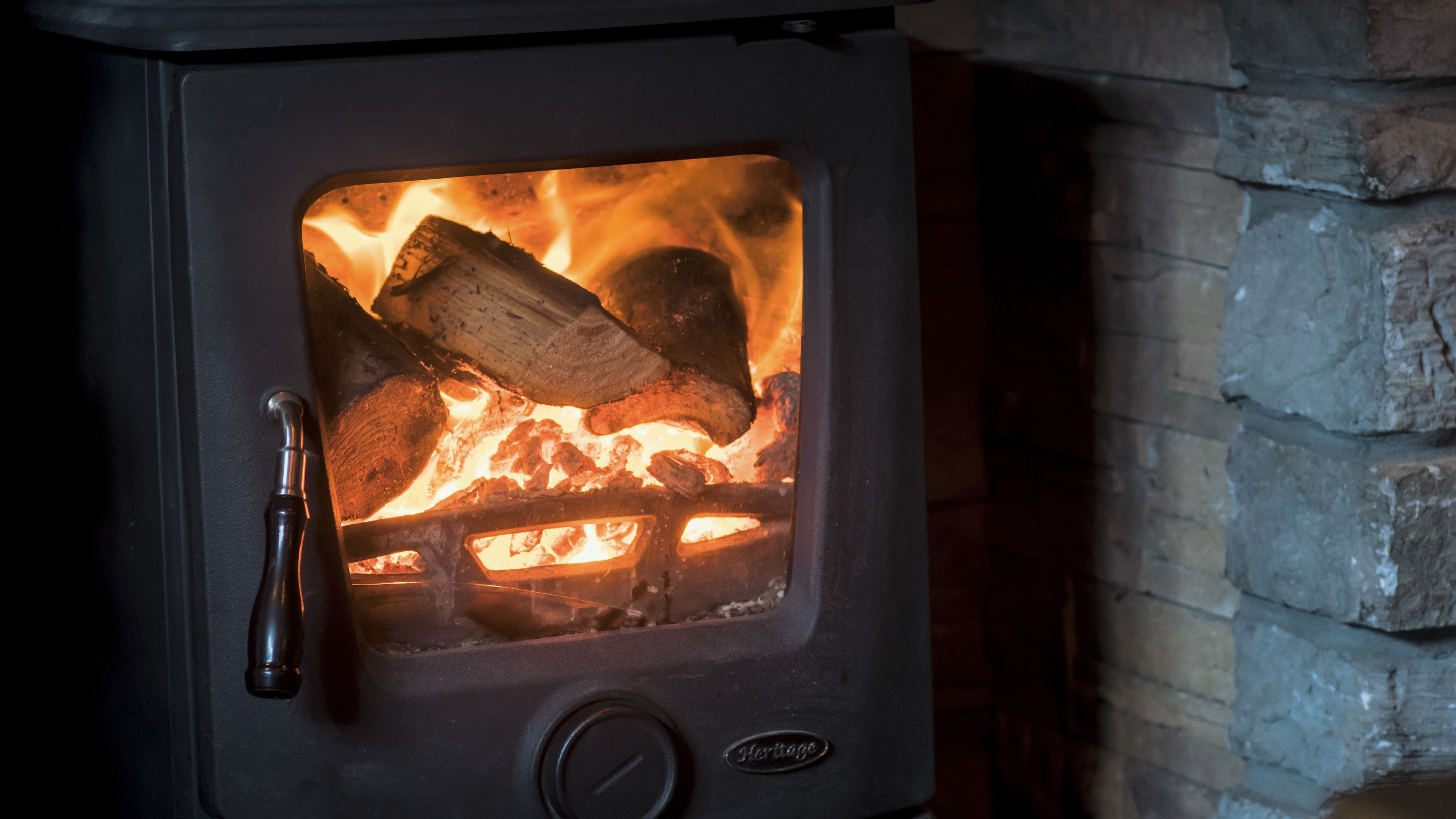 A wood-burning stove with a visible fire burning logs inside.