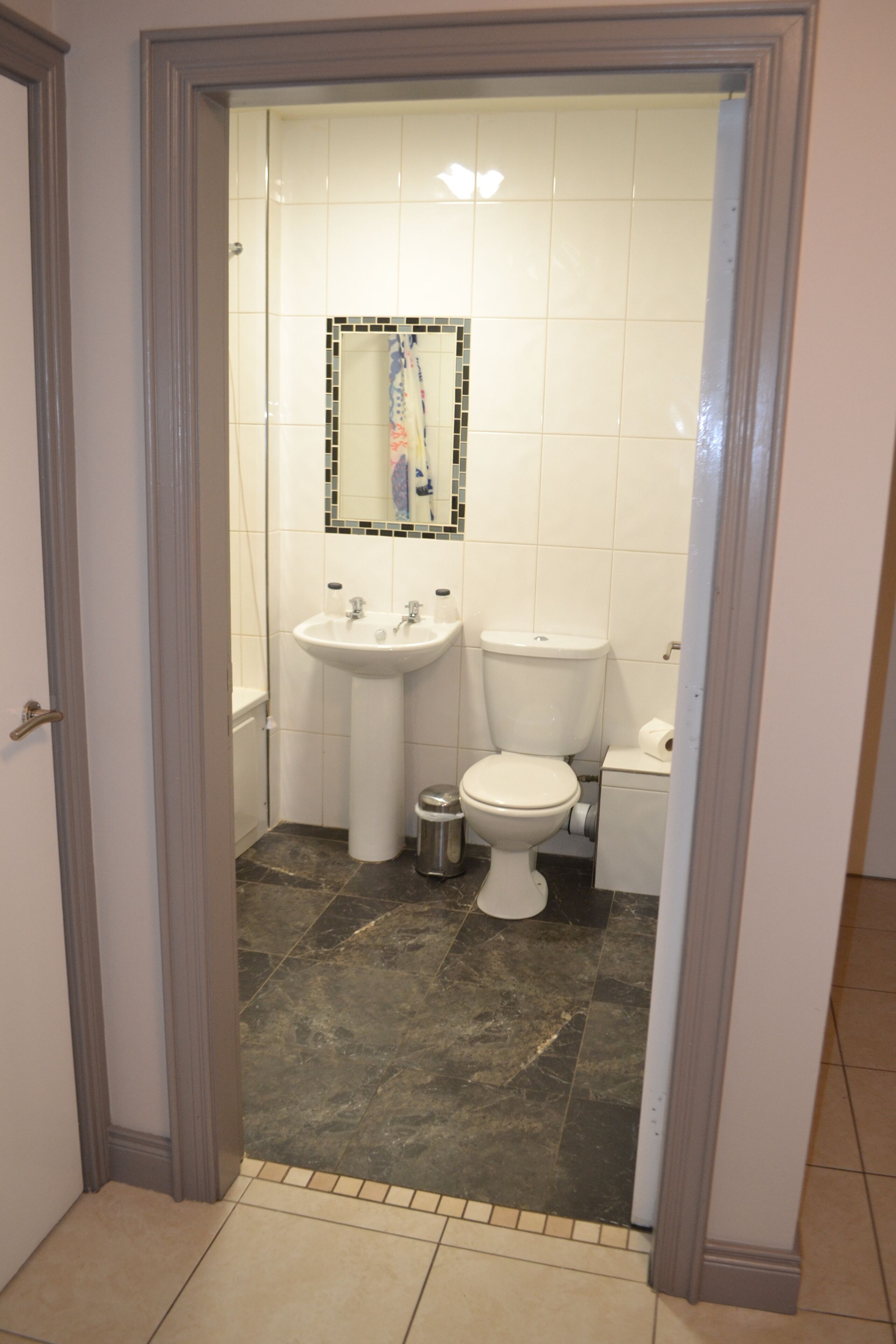 A bathroom with a white sink, toilet, and mirror.