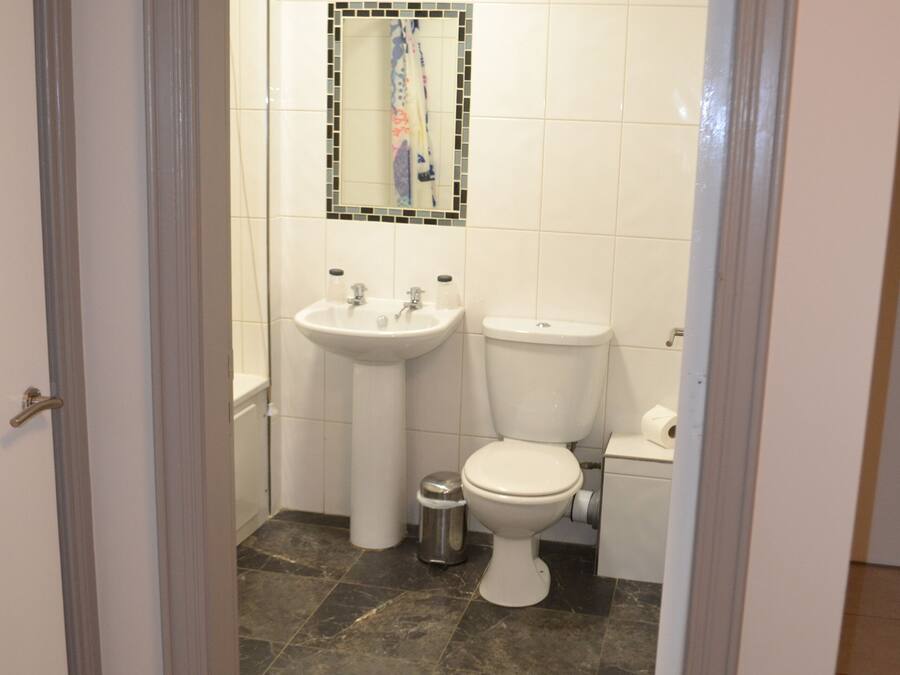 A bathroom with a white sink, toilet, and mirror.