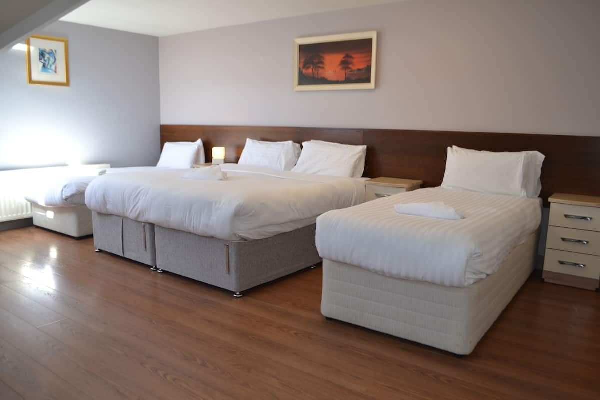 A hotel room with two beds, a wooden floor, and a painting on the wall.