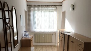 A room with a wooden table, a radiator, a window with curtains, and a cabinet. - G ästehaus Fries (Blankenheim)