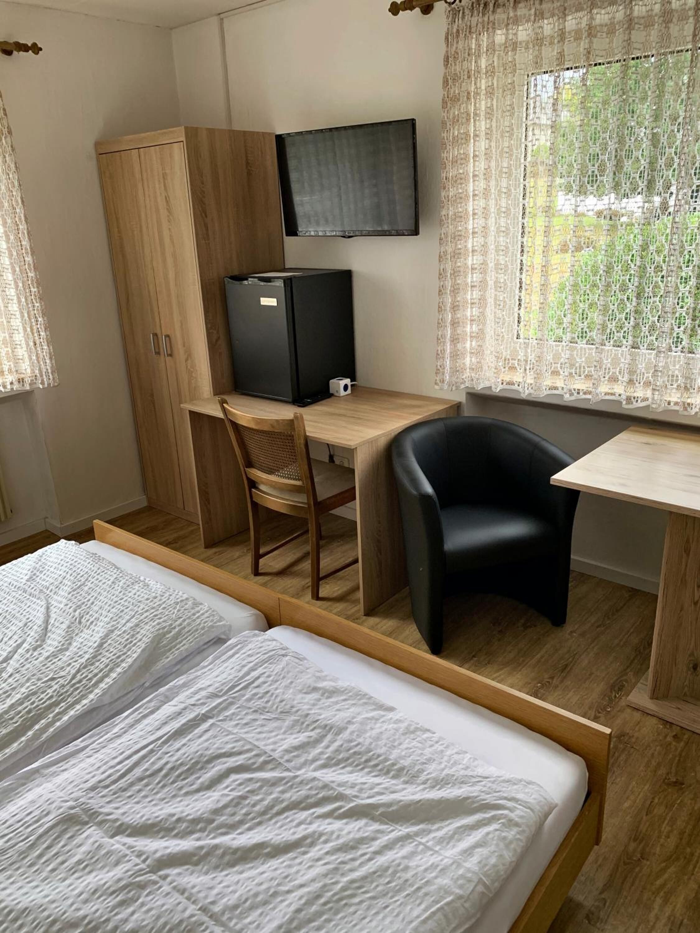 Une chambre à coucher comprenant un lit, un bureau avec un ordinateur, une chaise et une armoire.