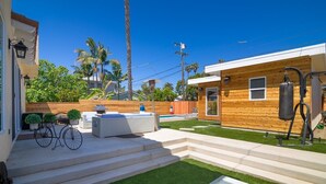 Eine moderne Terrassengruppe im Freien mit Holzdeck, einer kleinen Sitzecke und freiem Blick auf die umliegende Bepflanzung und Palmen.