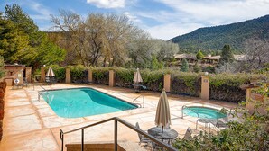 Un área de piscina con dos piscinas, sillones de descanso y sombrillas.