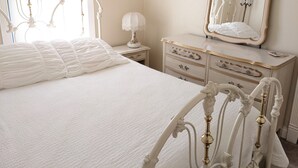 A bedroom with a bed, dresser, mirror, lamp, and curtains.