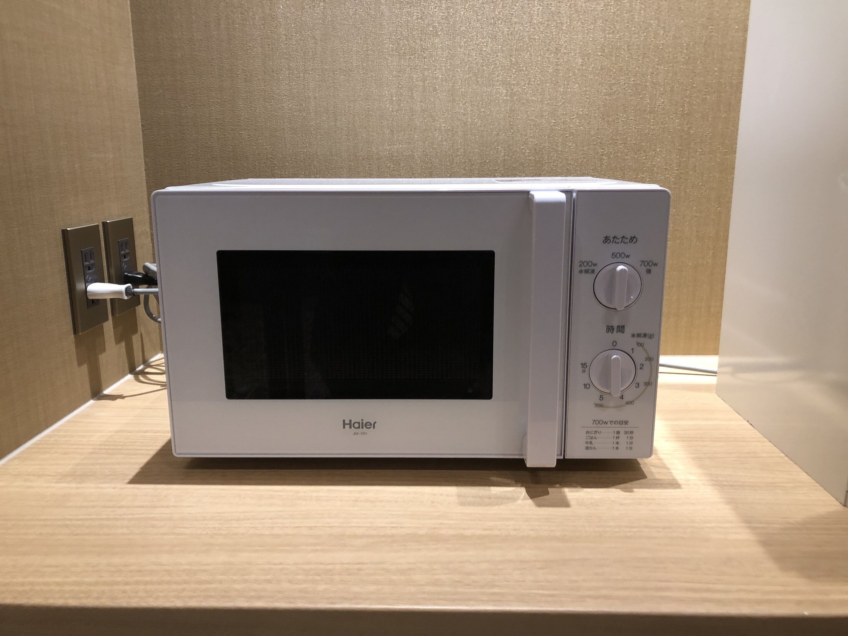 Un horno microondas Haier con pantalla digital y panel de control, sobre una superficie de madera.