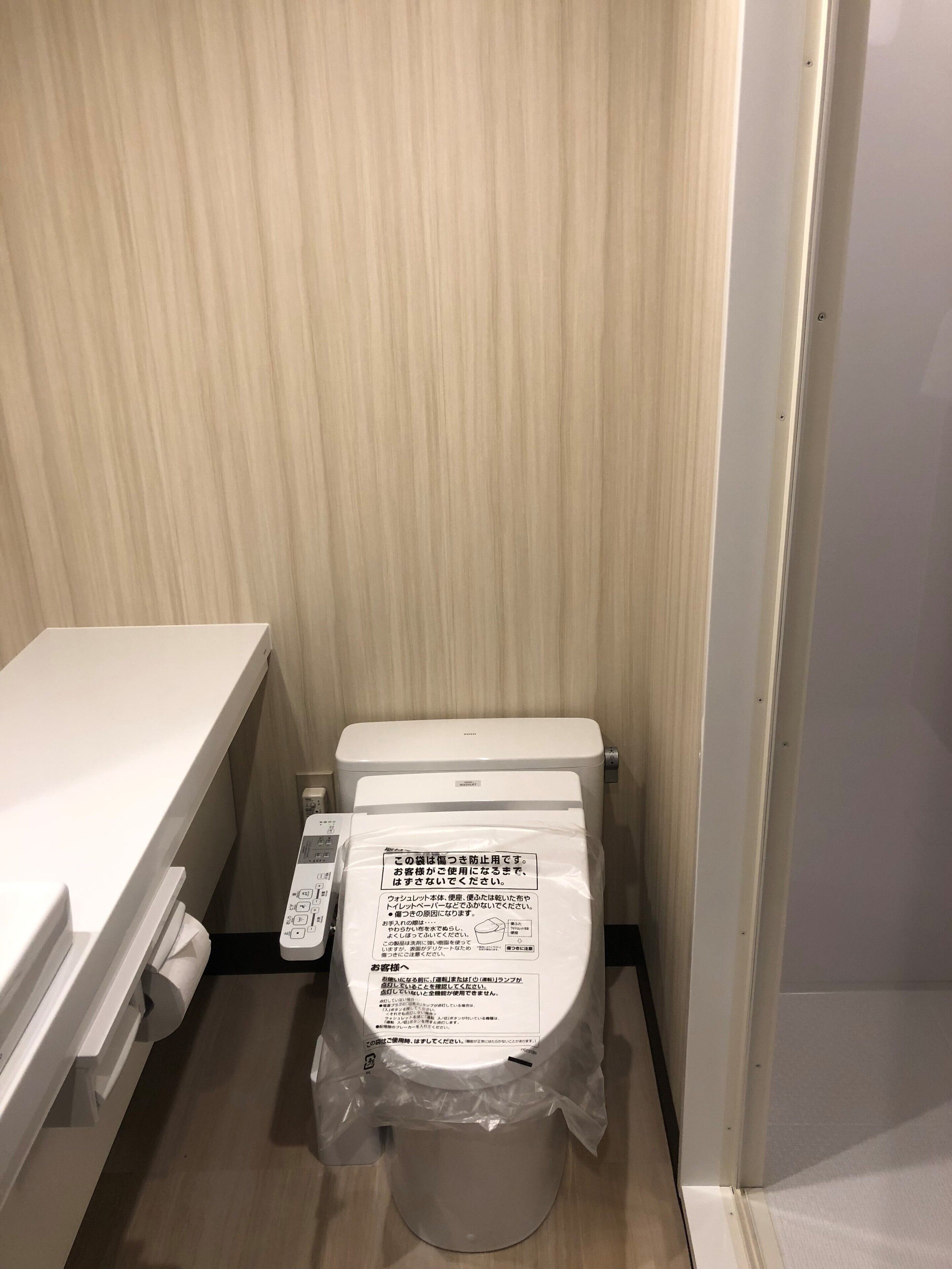 A small, compact bathroom with a toilet, a white sink, and a wooden wall.