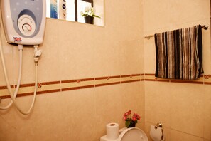 A bathroom with a toilet, a towel rack, a mirror, and a water heater. - Sherry Homes Raha Westlands (Nairobi)