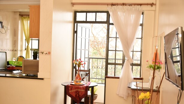 A kitchen with a stove, a sink, and a window with curtains. - Sherry Homes Raha Westlands (Nairobi)