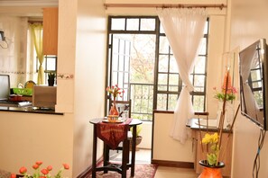 A kitchen with a stove, a sink, and a window with curtains. - Sherry Homes Raha Westlands (Nairobi)