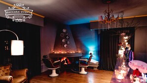 A cozy room with a fireplace, two leather armchairs, a dining table, and a bar area with a chandelier. - Assteas Bed & Breakfast (Montesarchio)