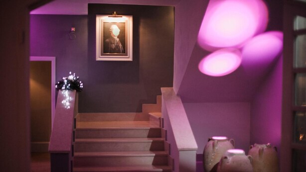 A staircase with a framed picture on the wall, a vase with lights, and a purple-lit room. - Assteas Bed & Breakfast (Montesarchio)