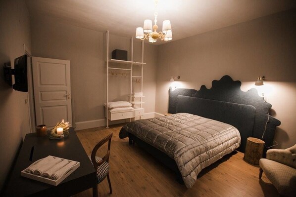 A bedroom with a bed, bedside table, chair, wardrobe, and a chandelier. - Assteas Bed & Breakfast (Montesarchio)