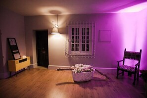 A room with a wooden floor, a white-framed window, a purple wall, a yellow cabinet, and a chair with a patterned cushion. - Assteas Bed & Breakfast (Montesarchio)