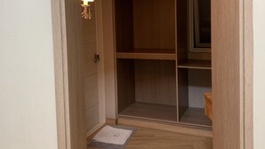 A narrow hallway with wooden flooring leading to a closet with open doors. - Tongyeong Camellia House (Tongyeong)