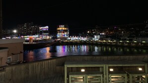 A waterfront view with wooden deck seating and a cityscape in the background. - Tongyeong Camellia House (Tongyeong)