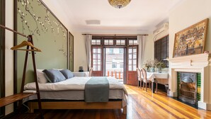 A bedroom with a wooden bed, a desk with a chair, a fireplace, and a view through a large window. - Yuyuan Impression Guesthouse (Shanghai)