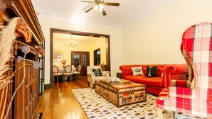 A living room with a red sofa, a plaid armchair, a wooden coffee table, and a patterned rug. - Yuyuan Impression Guesthouse (Shanghai)