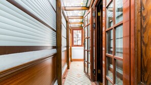 A narrow hallway with wooden paneling, a tiled floor, and a glass door leading to a room. - Yuyuan Impression Guesthouse (Shanghai)