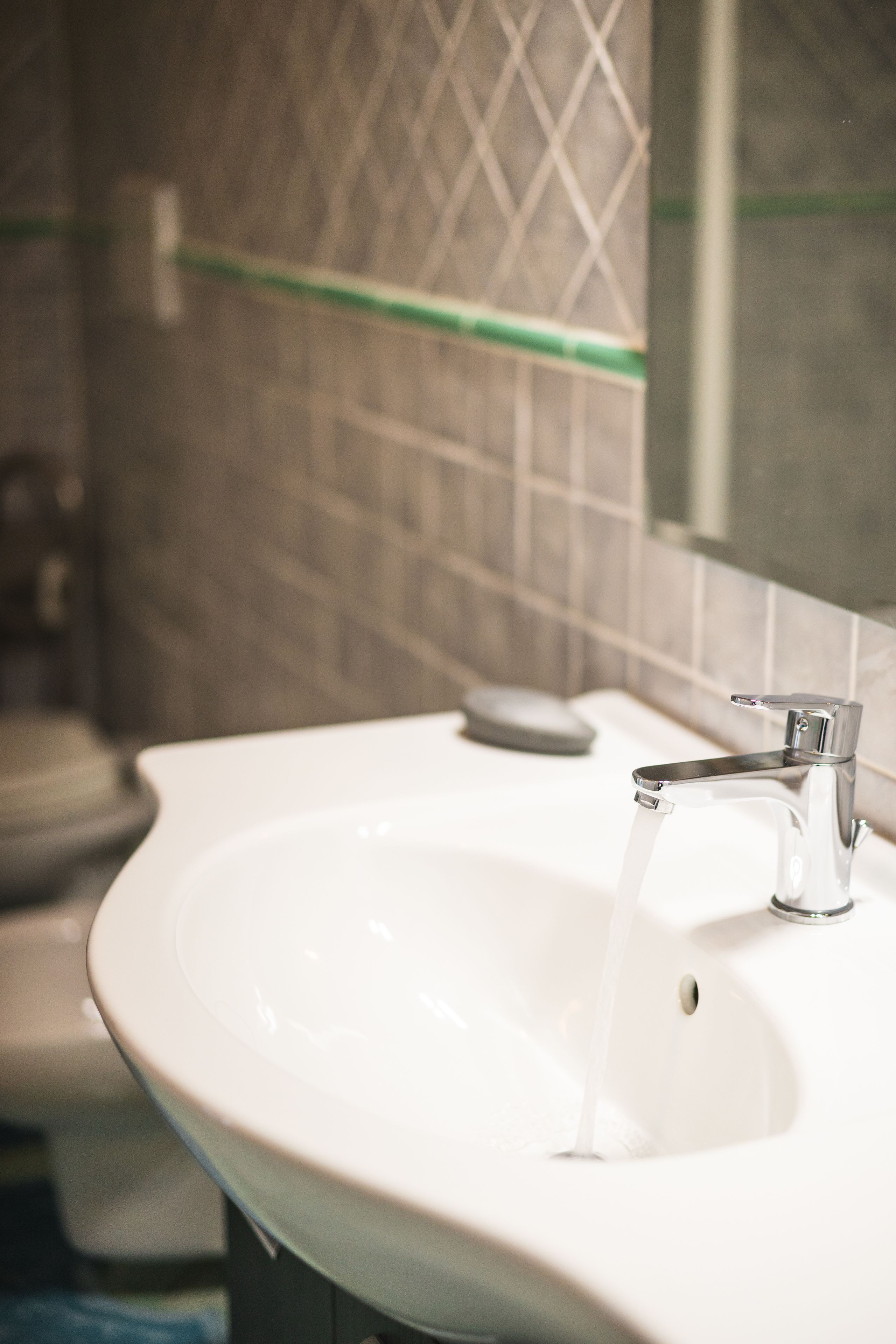 A bathroom sink with running water, a soap dish, and a mirror above it.