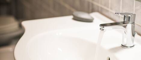 A bathroom sink with running water, a soap dish, and a mirror above it.