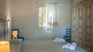 Ein Schlafzimmer mit einem Bett, einem Nachttisch mit Lampe, einem Fenster mit Vorhängen und einem Kleiderschrank.