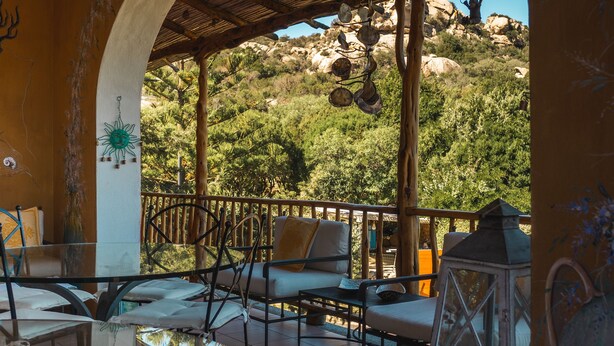 Ein überdachter Außenbereich mit Tisch und Stühlen, einem dekorativen Laternen und Blick auf eine Berglandschaft.