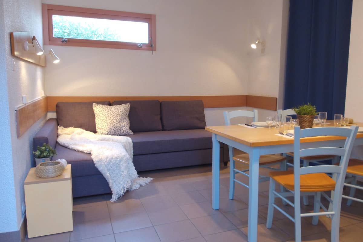 Una zona d'estar acollidora amb un sofà, una taula petita i cadires.