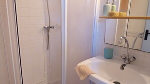 Een badkamer met een douche, wastafel en spiegel.