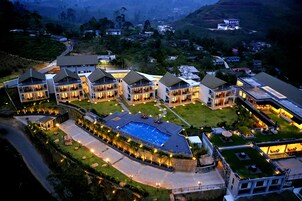 Un hotel moderno con varias edificaciones, una piscina central y caminos bien iluminados.