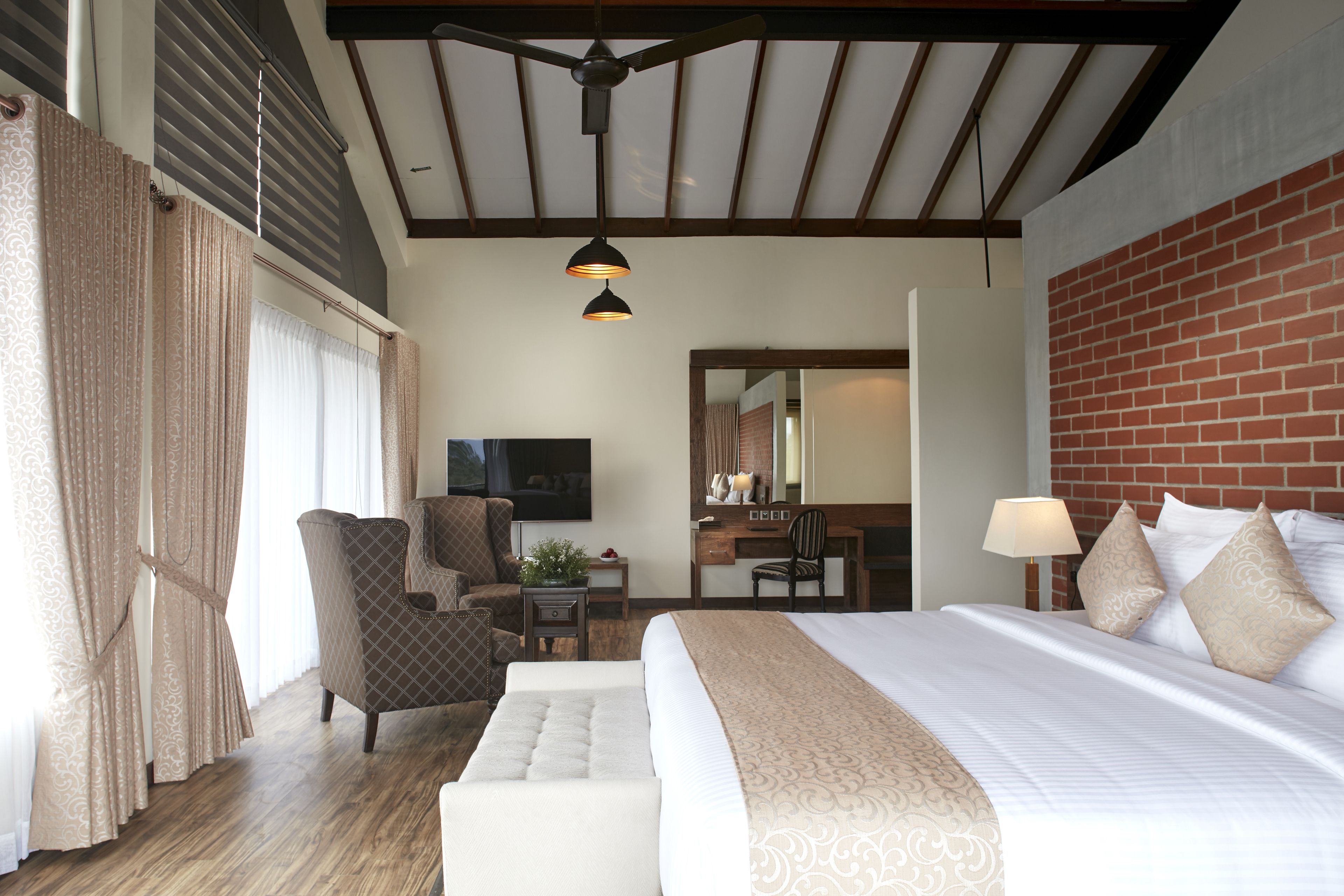A hotel room with a bed, a desk, a chair, and a television.