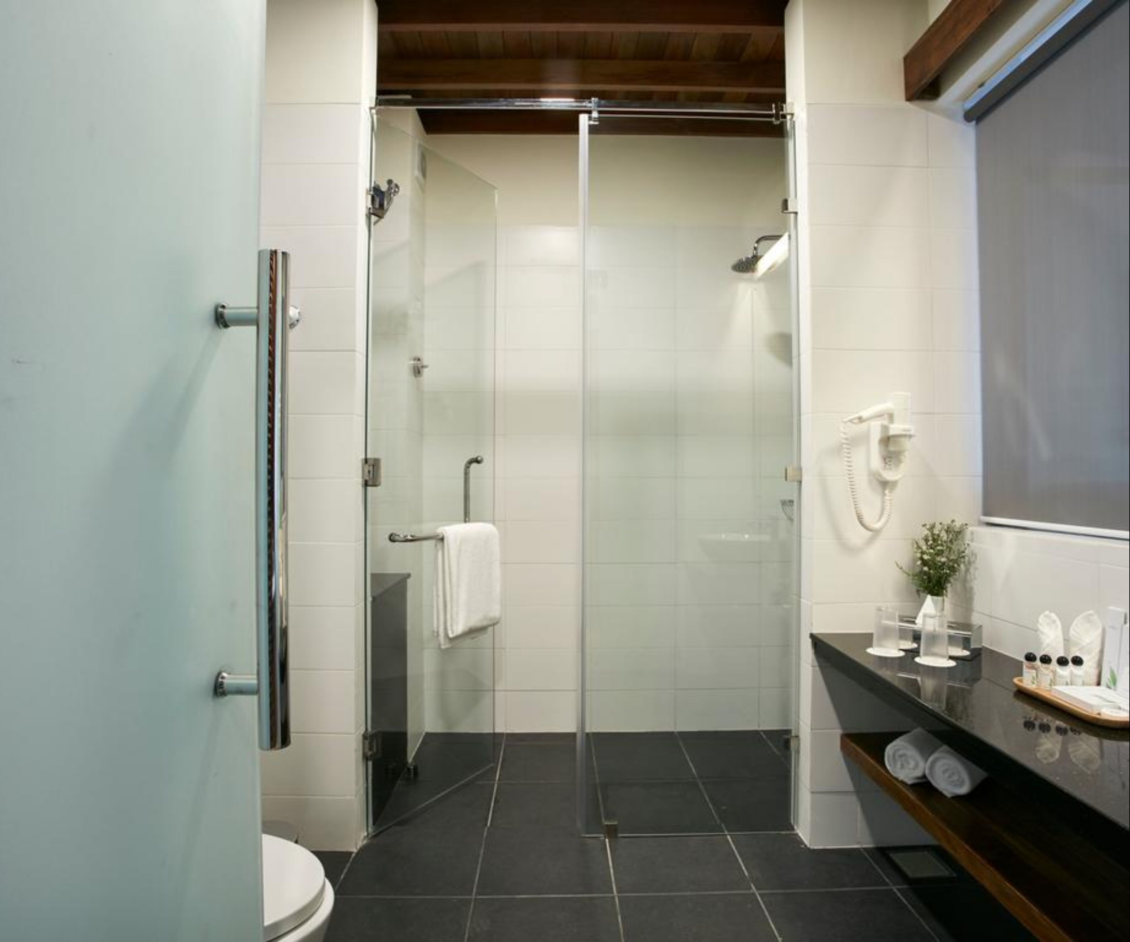 Un baño moderno con ducha acristalada, inodoro y tocador con artículos de aseo.
