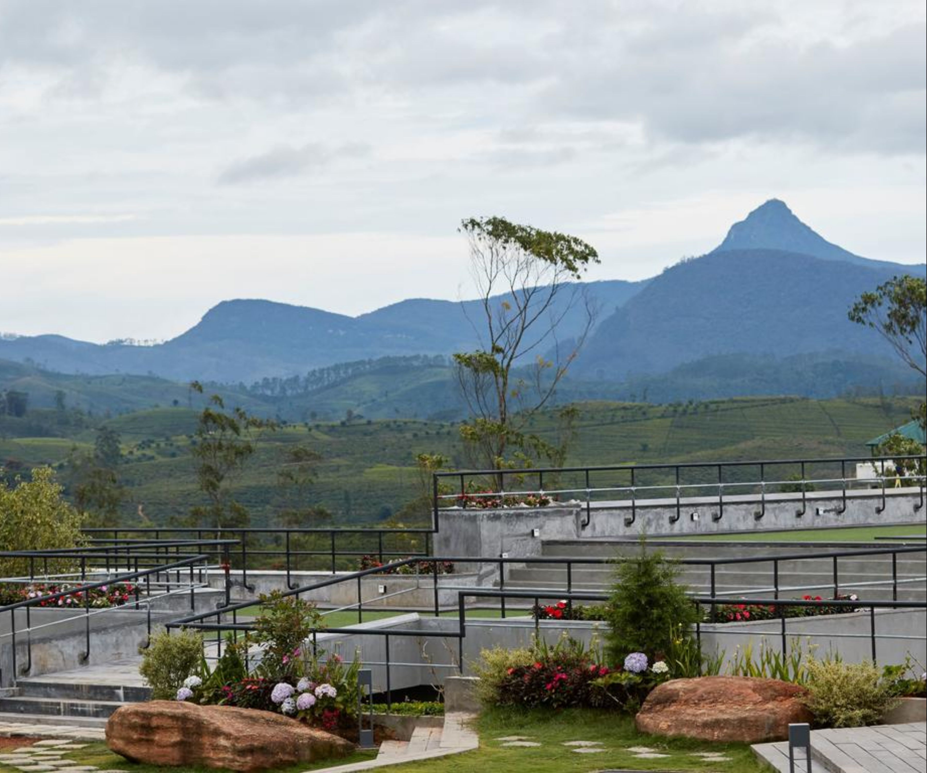 Una terraza ajardinada con vistas a montañas distantes, mobiliario exterior y un sendero de piedra.