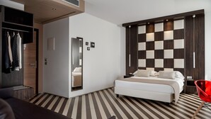 Una habitación de hotel moderna con una cama grande, un armario, un espejo y una silla roja.