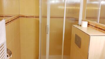 A bathroom with a shower enclosure, a toilet, and a sink.
