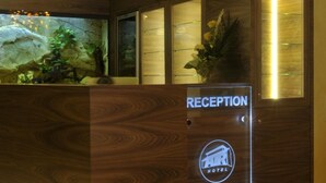 Una reception con scrivania in legno, insegna della reception e un piccolo acquario con piante.