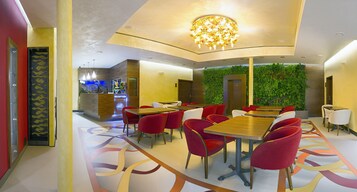 Un restaurante moderno con sillas rojas, una mesa de madera y una pared verde.