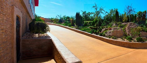 A curved driveway leading to a building with stone walls and a red awning.