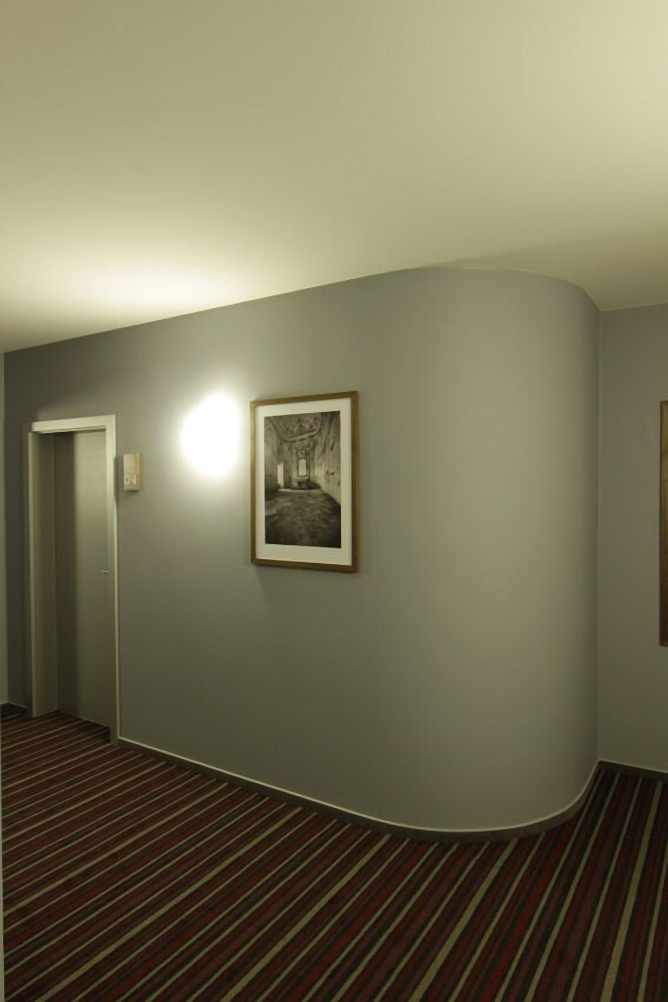 Ein Korridor mit Teppichboden, einem gerahmten Bild an der Wand und einer Tür links.