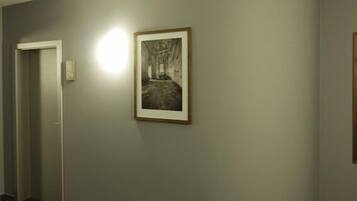 Ein Korridor mit Teppichboden, einem gerahmten Bild an der Wand und einer Tür links.